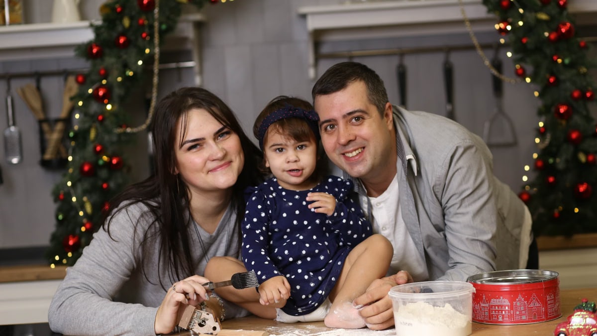 Happy family baking Christmas cookies together in a decorated kitchen.
